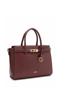 Sac à main en cuir marron foncé avec deux poignées, ferrures dorées, fermeture à boucle avant et pendentif décoratif avec logo.