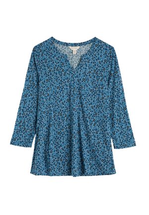 Túnica azul con escote en V, con un patrón floral en negro, amarillo y blanco. Mangas largas y ajuste suelto. Textura de tela suave.