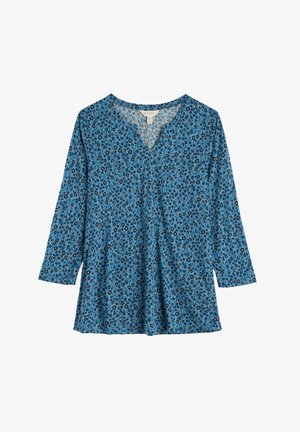 Túnica azul con escote en V, con un patrón floral en negro, amarillo y blanco. Mangas largas y ajuste suelto. Textura de tela suave.