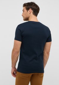 Granatowa, krótko rękawowa koszulka z bawełny, okrągłym dekoltem i dopasowanym krojem, wyświetlona z tyłu, ukazująca gładką fakturę.