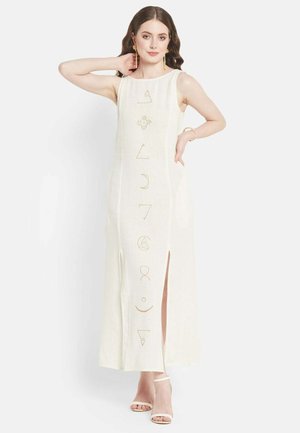Cremfarbendes Maxikleid mit geradem Schnitt, das goldfarbene geometrische Symbole auf der Vorderseite und seitliche Schlitzöffnungen für eine angenehme Bewegungsfreiheit aufweist.