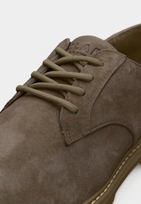 Μπεζ δερμάτινο παπούτσι με κορδόνια, στρογγυλή μύτη, εμφανείς ραφές και λαστιχένια σόλα με λευκή διακοσμητική ραφή.