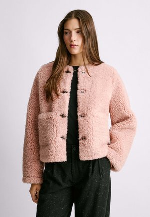 Rosa Kunstpelzjacke mit kastigem Schnitt, langen Ärmeln, großen Fronttaschen und metallenen Verschlüssen in der Mitte. Gefragt über einem schwarzen Oberteil.