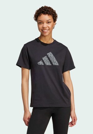 Camiseta de algodón negra con un gran logotipo de Adidas en patrón de leopardo gris en el frontal, mangas cortas y un corte relajado.