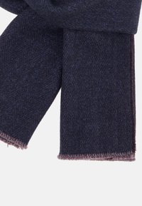 Námořnická modrá tkaná šála se vzorem rybí kosti, s neupravenými okraji a měkkou texturou. Materiál vypadá teplý a odolný.