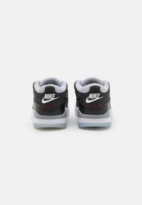 Sneakers Nike in pelle nera con rivestimento grigio, una suola intermedia bianca e icone Nike distintive; progettati con un profilo low-top.