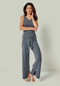 Graues Strick-Loungewear-Set bestehend aus einem ärmellosen Oberteil und weit geschnittenen Hosen mit einem Bindegurt, die seitliche Schlitze und eine weiche Textur aufweisen.