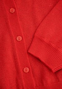 Czerwony dzianinowy kardigan z prążkowanymi brzegami i sześcioma okrągłymi guzikami. Tekstura jest gładka, z lekko błyszczącym wykończeniem.