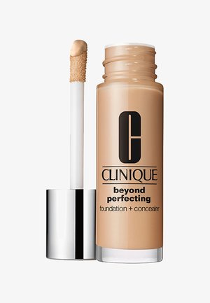 Fondotinta e correttore Clinique Beyond Perfecting in una boccetta di vetro trasparente. Liquido curvo beige con un applicatore bianco e un cappuccio con riflessi argentati.