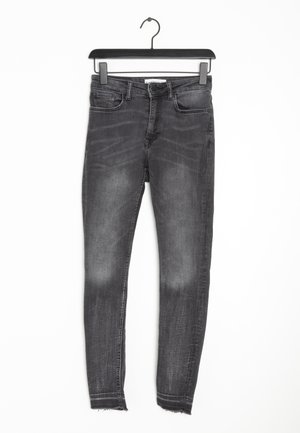 Slim-fit, zwarte spijkerbroek met een verweerd uiterlijk, rafelige zoom, vijf zakken ontwerp en metalen knoopsluiting. De stof lijkt op denim.