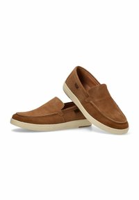 Zapatos slip-on de ante marrón con una superficie texturizada, punta redonda y una suela de goma blanca contrastante. Diseño minimalista sin hardware visible.