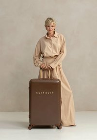 Bruine harde koffer met gouden letters "SUITSUIT," met een gladde textuur, uitschuifbare handgreep en vier wielen.
