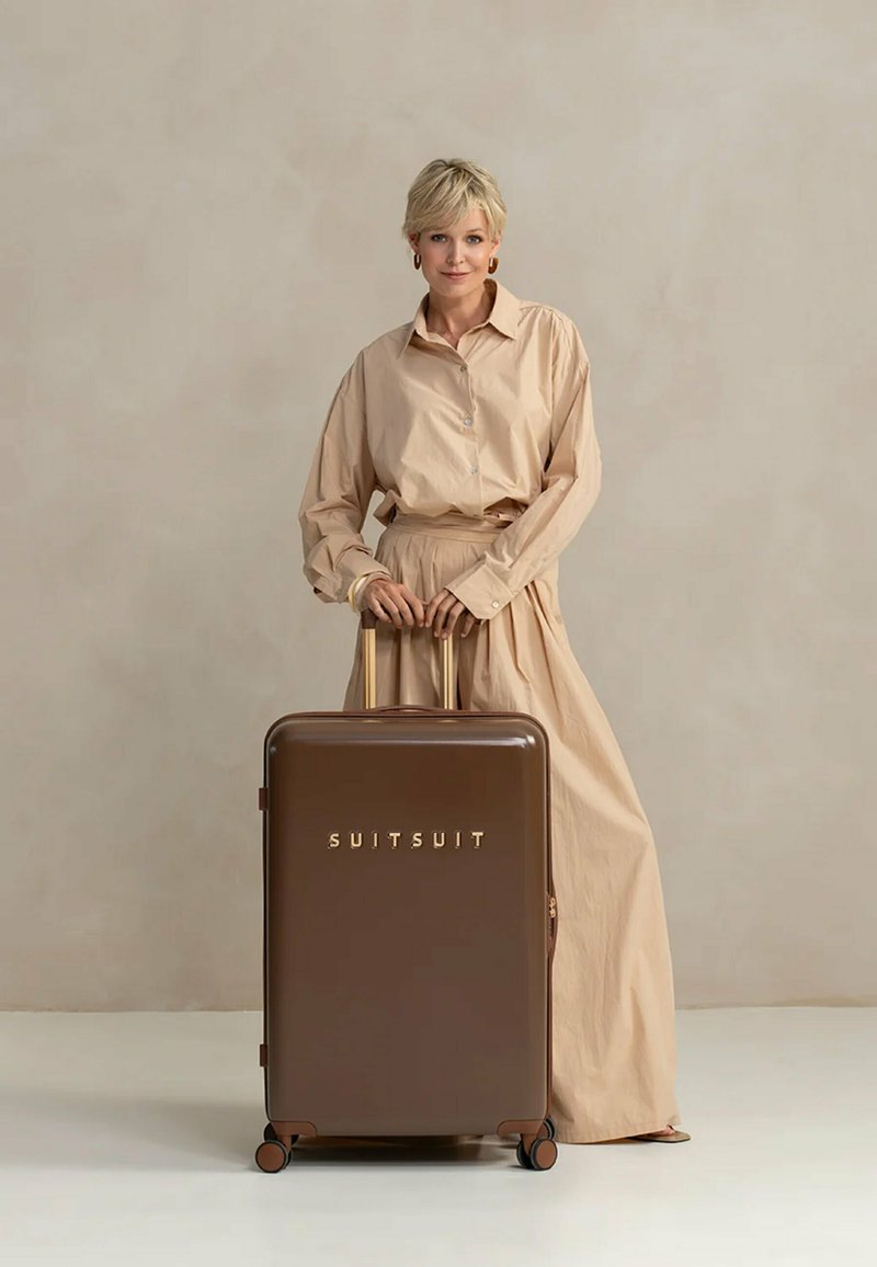 Bruine harde koffer met gouden letters "SUITSUIT," met een gladde textuur, uitschuifbare handgreep en vier wielen.
