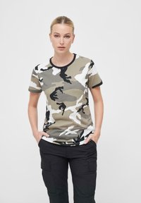 Kamuflasje t-skjorte med beige, grønn, svart og hvit mønstre, rund hals med svart trim, korte ermer, myk stoff, avslappet passform.