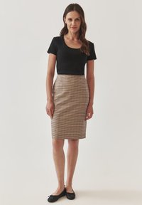 Černé tričko s krátkými rukávy v kombinaci s kostkovanou tužkovou sukní ke kolenům v béžové, hnědé a jemně červené barvě. Celý outfit doplňují černé balerínky.
