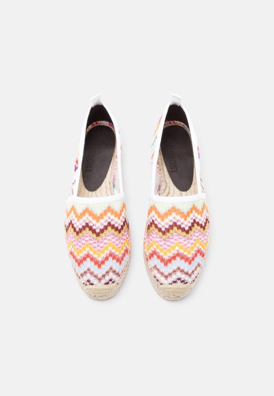 Paire d'espadrilles slip-on avec un motif en maille zigzag multicolore, bordure blanche, et semelle en jute naturelle sur un fond clair.