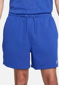 Blåa sportshorts i bomull med resårmidja, justerbar dragsko, sidofickor och en liten logotyp vid fållen.