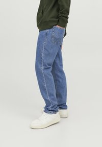Ljust blå denimjeans med rak skärning, som har en bakficka och subtila sömnadsdetaljer. Matchas med vita sneakers.