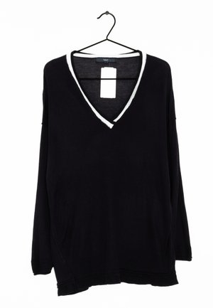 Pull noir à manches longues avec col en V et bordure blanche sur l'encolure, suspendu à un cintre noir avec une étiquette de prix attachée.