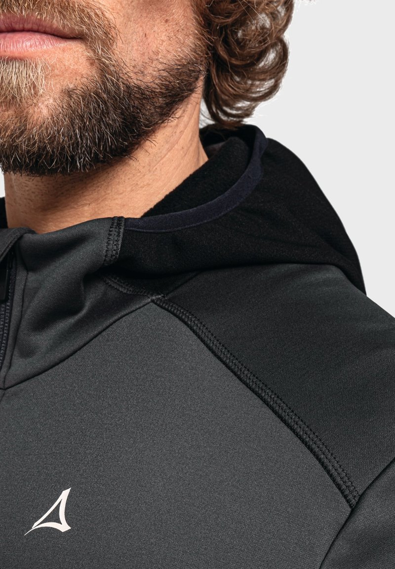Schwarzer Hoodie aus einem glatten, dehnbaren Material mit kontrastierenden matten und glänzenden Texturen. Auffällige Nähte und Logo-Detail auf der Brust.