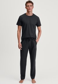Zwarte katoen T-shirt met ronde hals, gecombineerd met zwarte joggers met zijzakken en een ontspannen pasvorm.