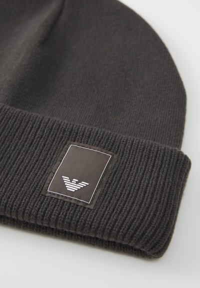 Gorro de malha cinza escuro com punho canelado, apresentando um logótipo retangular em preto e branco com um gráfico de pássaro.