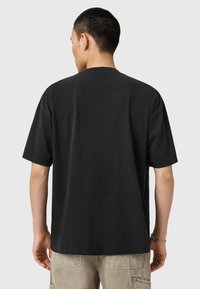 Sort bomulds-T-shirt med løs pasform, korte ærmer og rund hals. Simpelt design uden synlige mønstre eller logoer.