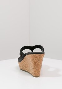 Černá korková sandál s klínem a texturovaným svrškem, s zakřiveným páskem a zúženým klínem pro stabilitu a pohodlí.