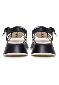 Černé kožené sandály s otevřenou zadní částí, trojúhelníkovým podpatkem a nastavitelným páskem. Měkká béžová stélka a kontrastní bílá podrážka.