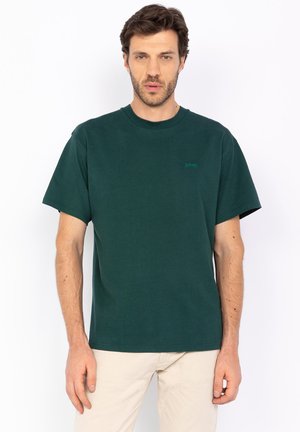 Donkergroen katoenen T-shirt met korte mouwen, een ronde hals en een klein groen logo op de linkerborst. Gladde textuur, relaxte pasvorm.