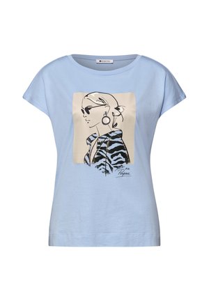 Camicia azzurra a maniche corte con una grafica di una donna che indossa occhiali da sole, orecchini a cerchio e una giacca a motivo zebrato, firmata "on Purpose."