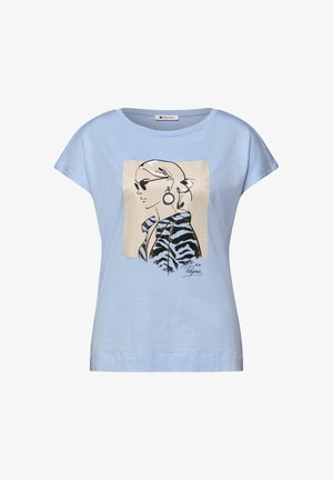 Camicia azzurra a maniche corte con una grafica di una donna che indossa occhiali da sole, orecchini a cerchio e una giacca a motivo zebrato, firmata "on Purpose."