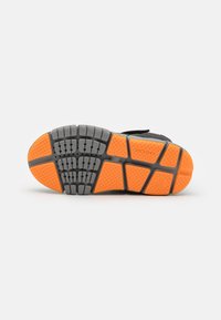 Soletta di scarpa nera con una combinazione di gomma grigia e arancione. Il design include motivi testurizzati per la presa e la durata.
