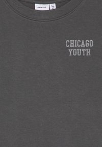 Felpa grigio scuro con collo a girocollo in costina e stampa in argento "CHICAGO YOUTH". Texture liscia, design casual, adatta per i giovani.