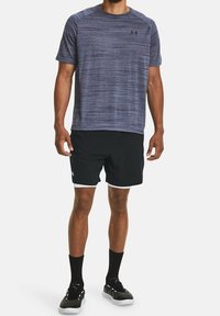 Männliches Sportoutfit: strukturiertes dunkelblaues Kurzarmhemd, schwarze Shorts mit weißen Trimm, schwarze Socken und sportliche schwarze Schuhe.