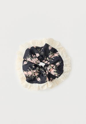 Crna tkanina gumica za kosu s ružičastim i zelenim cvjetnim uzorkom, okružena kremastom čipkom s detaljima izbušenih rupa, na bijeloj pozadini.