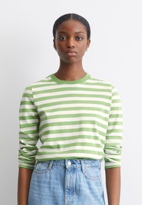 Groene en witte gestreepte blouse met lange mouwen en een ronde hals, gemaakt van zachte stof. Gemaakt in combinatie met lichtblauwe denimshorts met hoge taille.
