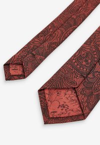 Crvena i crna kravata s paisley uzorkom, izrađena od glatkog materijala, sa oštrim rubovima i složenim detaljima na obje strane.