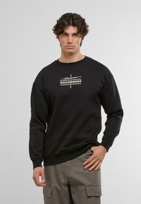 Sudadera de algodón negra con puños y dobladillo acanalados, que presenta un logotipo gráfico blanco centrado en el pecho con una fuente en negrita.