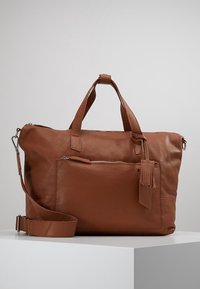 Bolso de cuero marrón con doble asa, correa de hombro desmontable, bolsillo con cremallera en la parte delantera y detalle de borlas. Textura suave, forma rectangular.
