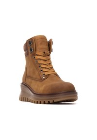Botas de tobillo de cuero marrón con cordones en la parte delantera, ojales reforzados y cremalleras laterales. Suela de goma gruesa y resistente con un ligero tacón.