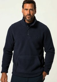 Pullover in fleece blu navy con collo a imbuto, dettagli in bottone e tasca frontale. Tessuto textured e vestibilità rilassata.