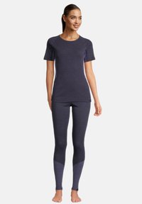 Marine atletisk top med korte ærmer, parret med matchende leggings. Leggings har en lysere marinefarve akcent nær anklerne. Glat, tætsiddende tekstur.