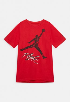 T-shirt rouge à manches courtes avec la silhouette noire d'un joueur de basket sautant et le mot « Flight » écrit en dessous en écriture blanche et noire.