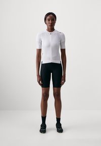 Weißes, kurzärmliges Radtrikot mit einem Frontreißverschluss, kombiniert mit schwarzen Radsportshorts. Glatte Textur und athletischer Schnitt, der für Leistung ausgelegt ist.