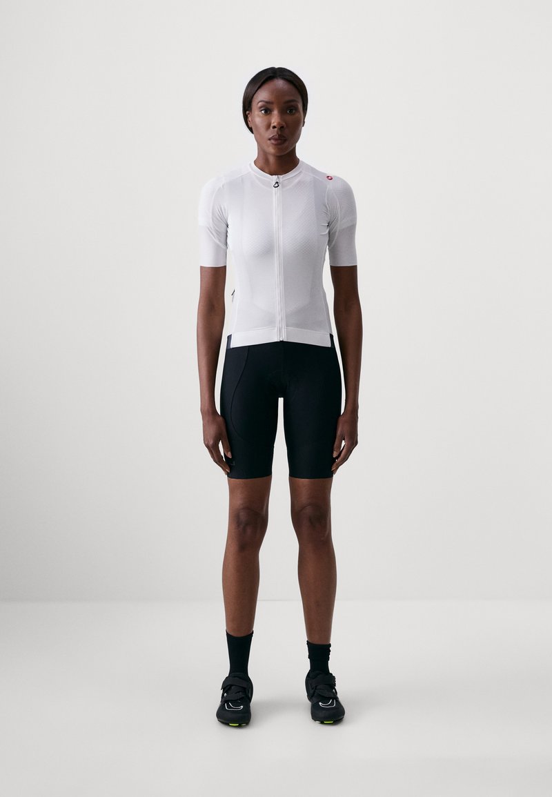 Weißes, kurzärmliges Radtrikot mit einem Frontreißverschluss, kombiniert mit schwarzen Radsportshorts. Glatte Textur und athletischer Schnitt, der für Leistung ausgelegt ist.