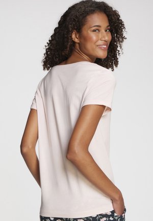 Light pink short-sleeve t-shirt with a relaxed fit, smooth texture, and a round neckline. Back view shows subtle detailing and rolled sleeves.