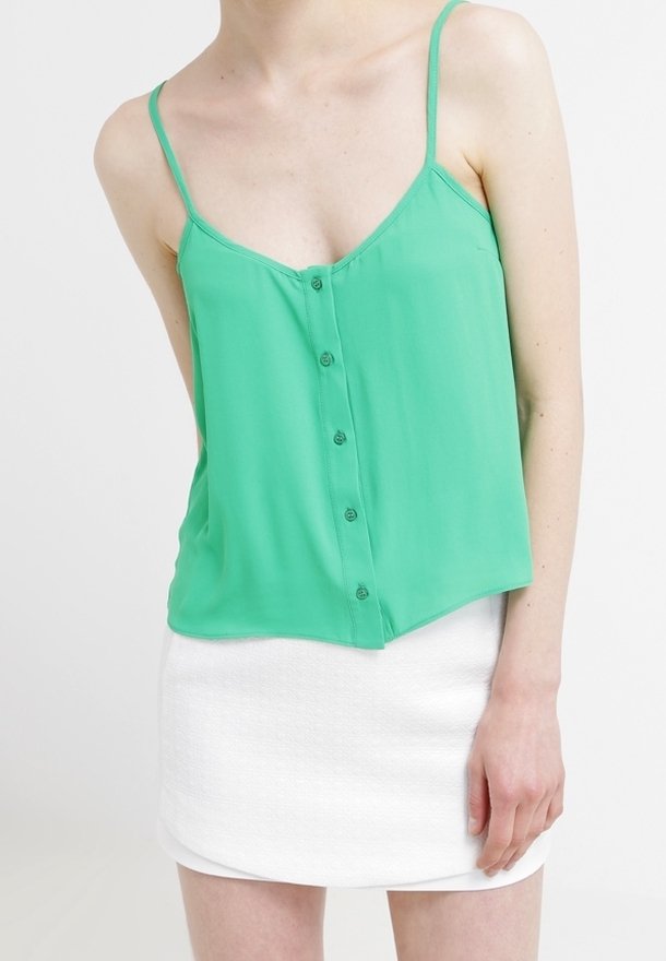 Zelený šifónový top bez rukávů s tenkými ramínky a detaily na knoflíky, kombinovaný s bílou texturovanou minisukní. Pohodlný střih, lehký materiál.