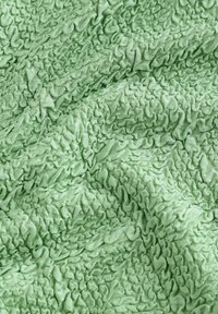 Tessuto verde strutturato con una superficie arricciata, caratterizzato da motivi ondulati e una finitura morbida e leggermente lucida.