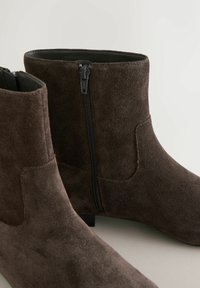 Bruine suède enkellaarsjes met een ritssluiting aan de zijkant en een lage blokhak, met een gladde textuur en een eenvoudig ontwerp.